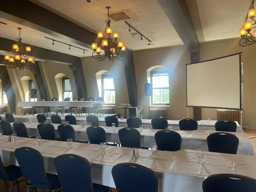 Salle montée en formation avec écran, projecteur et table d'honneur sur scène au Complexe d'affaires Le 905