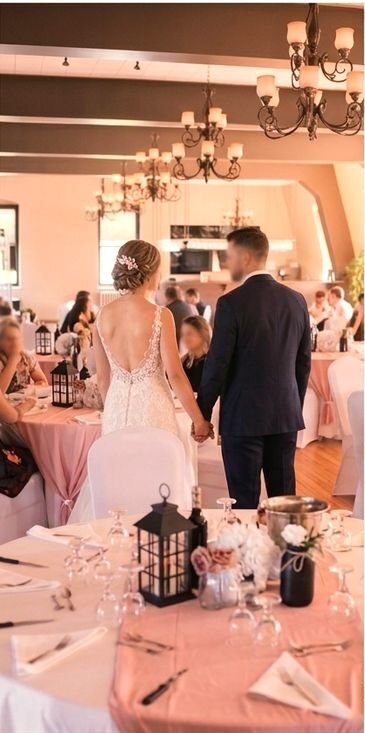 Mariés main dans la main dans une salle de réception décorée en rose au Complexe d'affaires Le 905